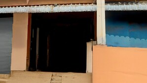 Un bâtiment avec une porte à volets fermés, une entrée visible et un toit en tôle ondulée.