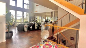 A spacious living area with a large window, a staircase, and a piano.