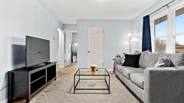 Ein modernes Wohnzimmer mit Flachbildfernseher, grauem Sofa und Glastisch.