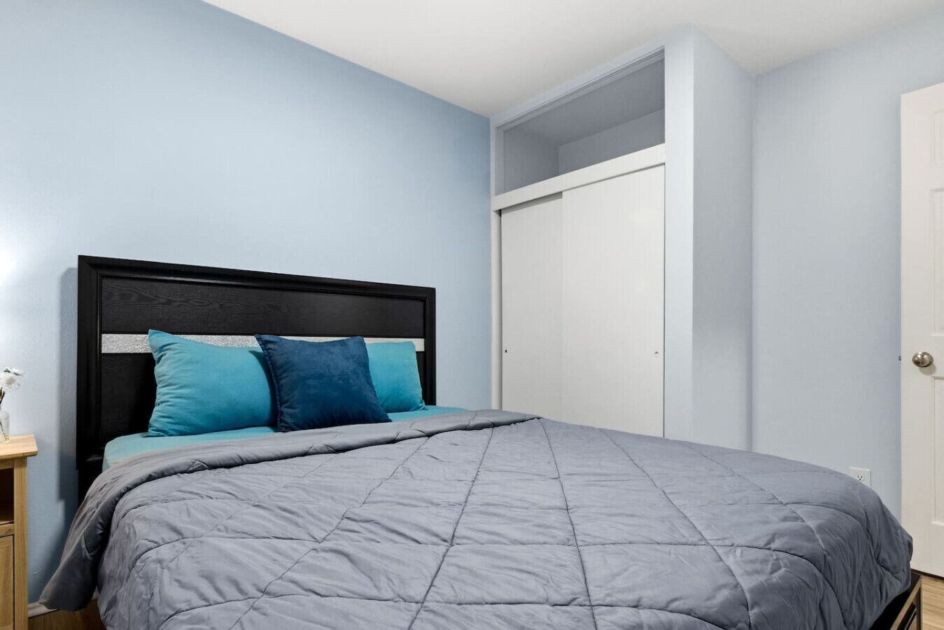 Een slaapkamer met een bed, nachtkastje en kledingkast.