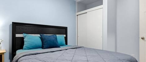 Een slaapkamer met een bed, nachtkastje en kledingkast.