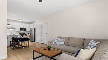 A modern living room with a sofa, coffee table, and a dining area with a table and chairs.