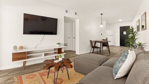 Un salon moderne doté d’un téléviseur à écran plat, d’un canapé, d’une table basse et d’un coin repas avec une table et des chaises.