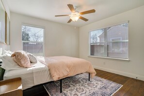 Ein Schlafzimmer mit einem Bett, einem Deckenventilator und großen Fenstern.