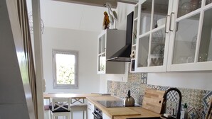 Une cuisine moderne avec des armoires blanches, un four encastré, un lave-linge et une fenêtre laissant entrer la lumière naturelle.