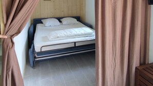 Une chambre à coucher avec un lit, une tête de lit en bois et un téléviseur fixé au mur.