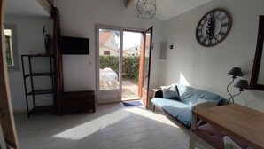 Une pièce comprenant un lit, un bureau, une télévision, une horloge et une porte donnant sur l’extérieur.