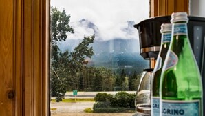 Vista a través de una ventana con paisaje montañoso, una carretera y una señal que indica una dirección.