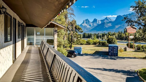 Un hotel con un área exterior techada, vistas a montañas y un letrero que dice The Gateway Inn Motor Lodge.