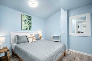 Ein Schlafzimmer mit Bett, Nachttisch, Wandspiegel und Deckenleuchte.