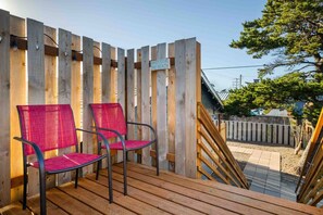 Eine Holzterrasse mit zwei Stühlen, einem Holzzaun und einem Schild mit der Aufschrift 'Barefoot at the Beach'.