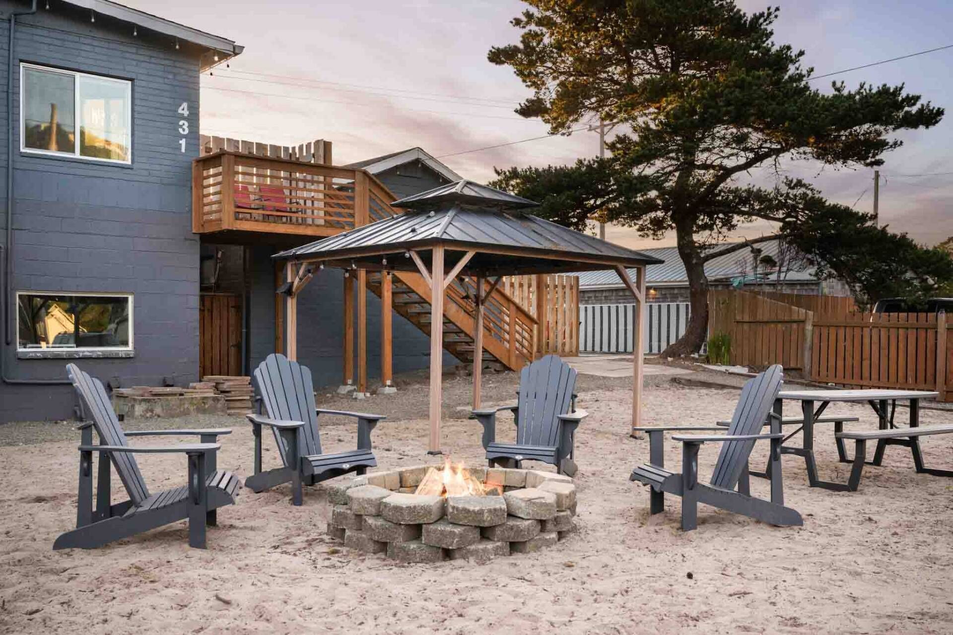 A patio area with Adirondack chairs, a fire pit, and a wooden pergola.