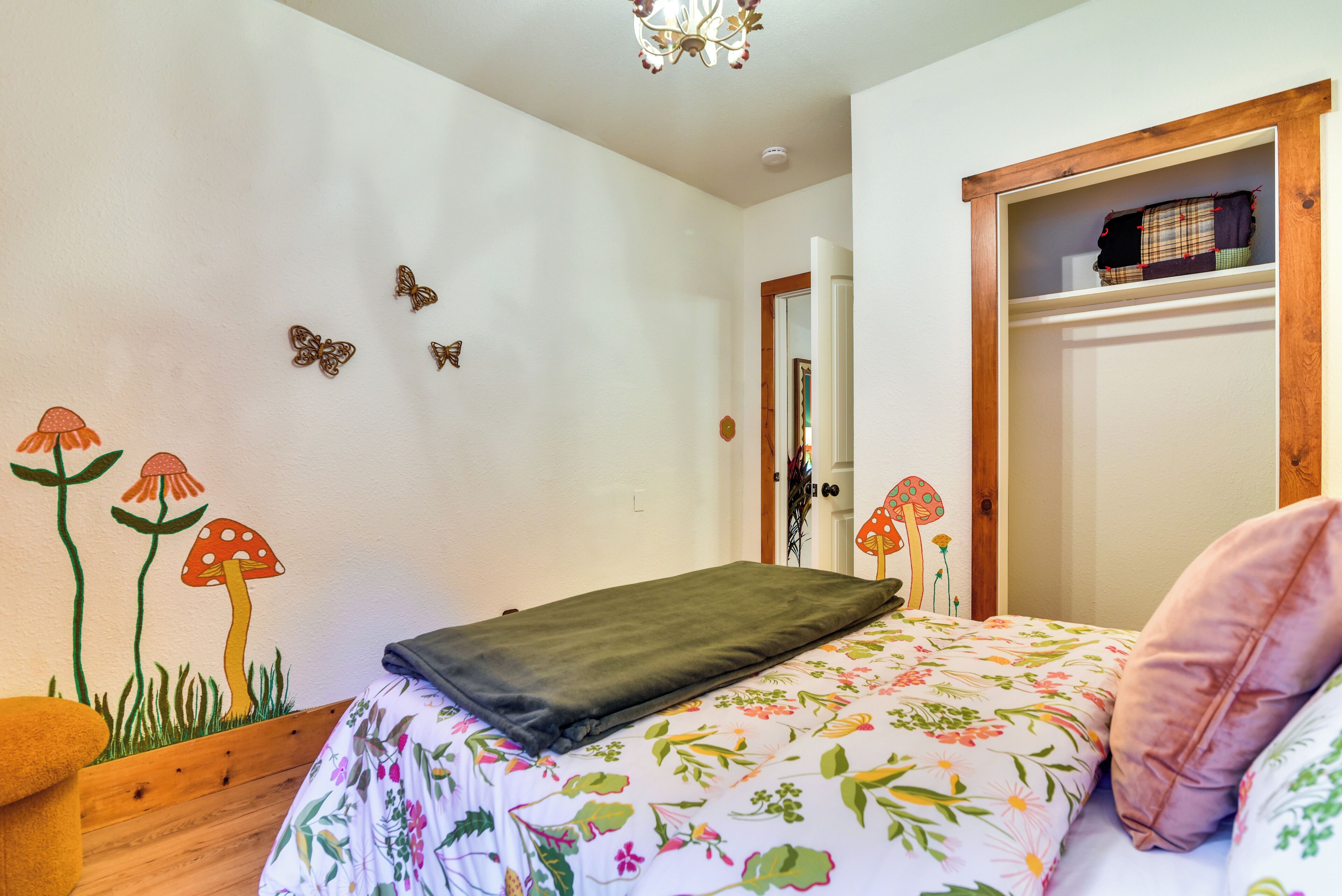 Une chambre à coucher avec une couvre-lit à motifs floraux, une tête de lit en bois et une porte dotée d’un miroir.