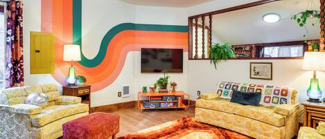 A retro-styled living room with two sofas, a coffee table, and a large mirror.