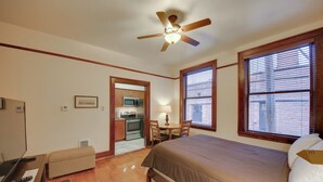 A hotel room with a bed, desk, chair, kitchenette, and a ceiling fan. - Epic Silver Valley Basecamp: Steps to Dtwn Fun! (Wallace)