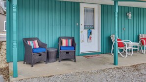 A turquoise wooden building with a white door, two wicker chairs with blue cushions, and a small table. - Walkable & Convenient Main Street Studio in Delphi (Delphi)
