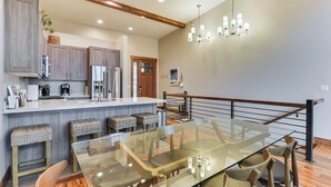 A modern kitchen with wooden cabinets, a central island, and a glass dining table with chairs. - Luxe Eden Gem w/ Hot Tub: 6 Mi to Powder Mountain! (Eden)