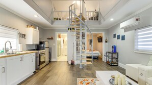 Eine geräumige Küche mit modernen Geräten, ein Essbereich mit einem weißen Tisch und eine Treppe, die zwei Ebenen verbindet.