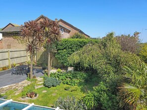 Ein Garten mit Pool, Terrassentisch und unterschiedlichen Pflanzen.