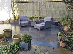 A patio area with wicker furniture, potted plants, and a wooden fence. - 3 bedroom accommodation in Newquay (Newquay)