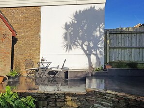 Eine Terrasse mit Tisch und Stühlen, eine Ziegelwand und ein Holzzaun.