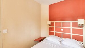 A hotel room with a bed, a nightstand, and a red accent wall. - Cannes Villa Francia - Maeva Home (Cannes)