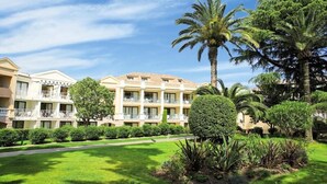 A hotel with multiple-story buildings, balconies, and lush greenery including palm trees and well-maintained lawns. - Cannes Villa Francia - Maeva Home (Cannes)