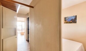 Un pasillo con una cama, una puerta y un cuadro en la pared.