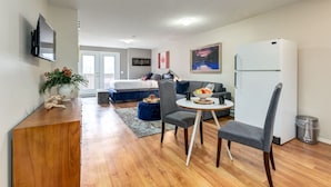 A compact living space with a kitchenette, a dining area with a small table and chairs, a sofa, a bed, and a TV mounted on the wall. - Cozy Condo in the Heart of Canmore (Canmore)