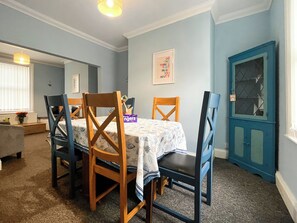 A dining area with a table set for four, wooden chairs, a blue door, and a framed motivational quote on the wall. - 3 bedroom accommodation in Scarborough (Scarborough)