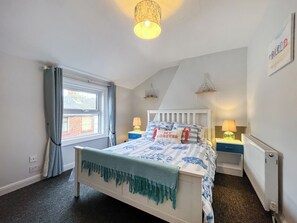 A bedroom with a bed, bedside tables, a lamp, a window with curtains, and a wall with a picture. - 3 bedroom accommodation in Scarborough (Scarborough)