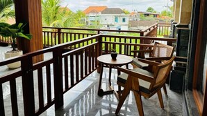 A balcony with wooden furniture, a small table, and potted plants. - Pondok Wisata Amerta Semaya Agung (Ubud)