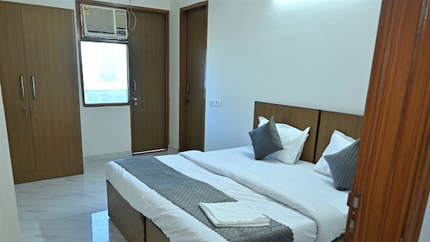 Une chambre à coucher avec un lit, une armoire en bois et une fenêtre équipée d’un climatiseur.