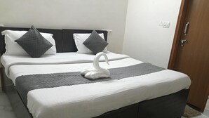 Un lit double avec une tête de lit sombre, une literie blanche et deux oreillers.