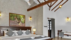 A bedroom with a large bed, a wooden headboard, a painting of leopards, and wall-mounted lights. - The Tusker's Hideout (Alawwa)