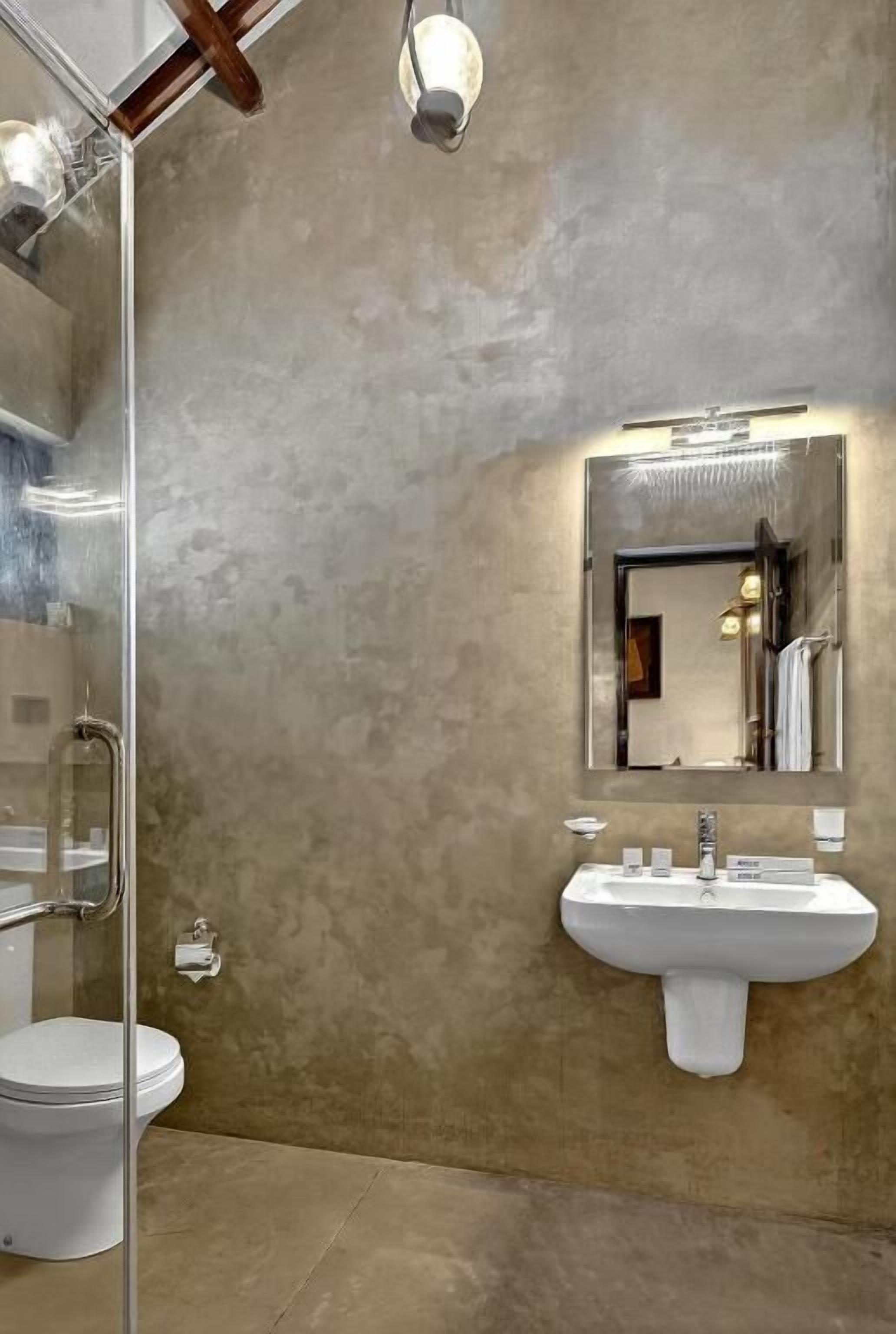 A bathroom with a glass shower enclosure, a white sink, and a large mirror.