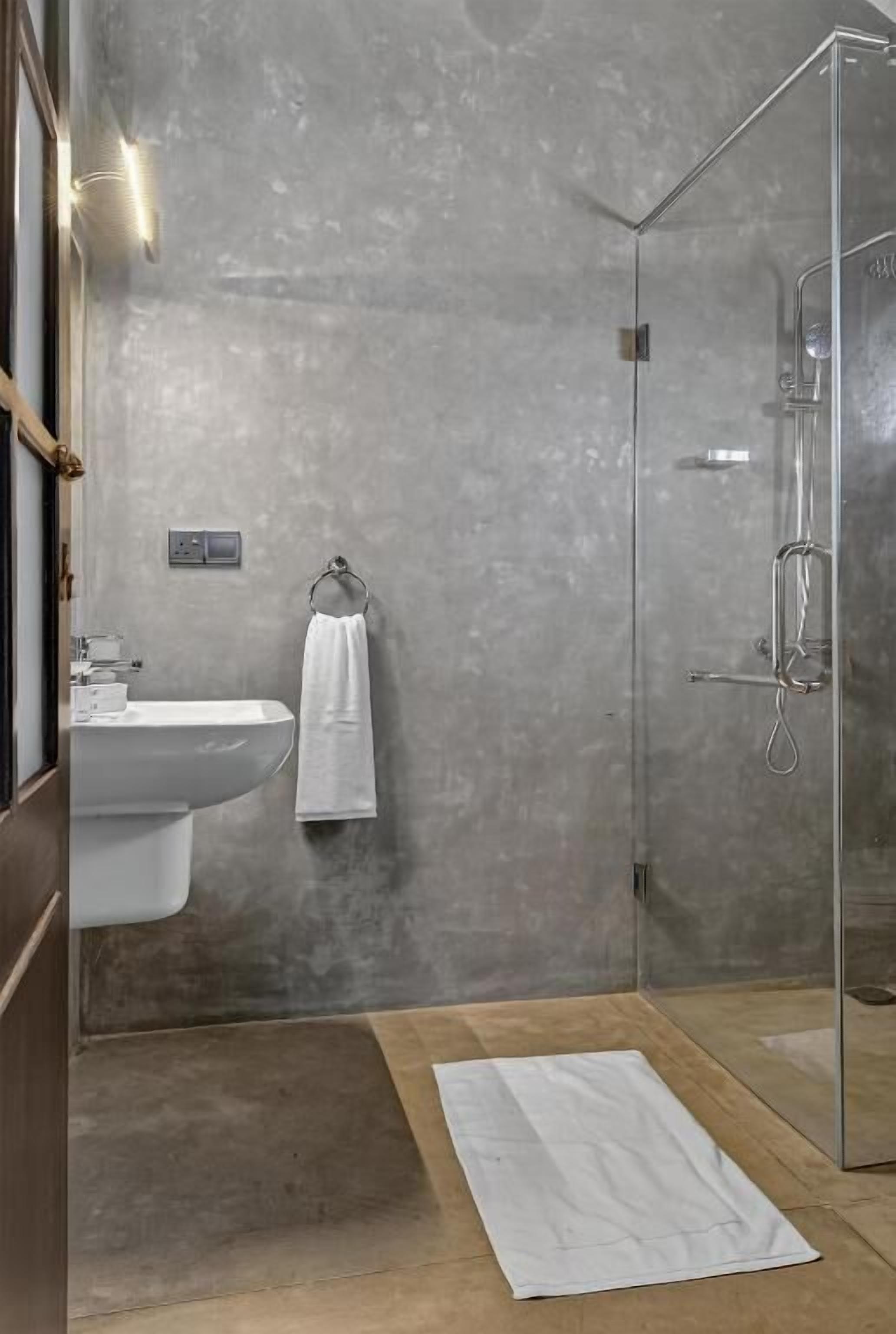 A modern bathroom with a glass-enclosed shower, a white sink, and a towel rack.