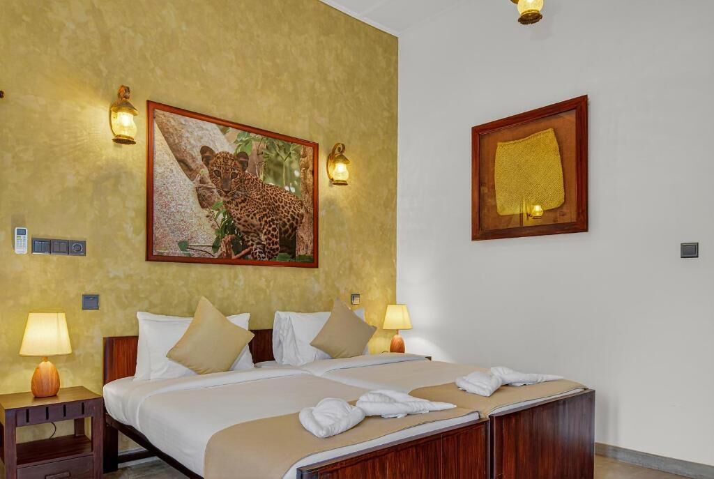 A hotel room with a large bed, two bedside tables with lamps, a painting of a leopard, and a framed picture on the wall.