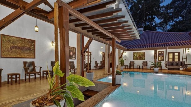 A pool area with wooden beams, chairs, and potted plants. - The Tusker's Hideout (Alawwa)