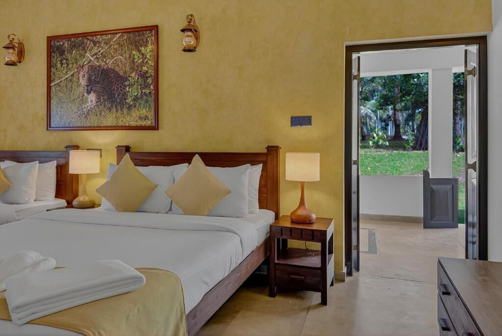 A hotel room with a large bed, two bedside tables with lamps, a painting of a leopard, and a door leading to an outdoor area.