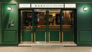 A hotel entrance with a green facade, double doors, and a tiled entrance area. - LUXIAINN (Tainan)