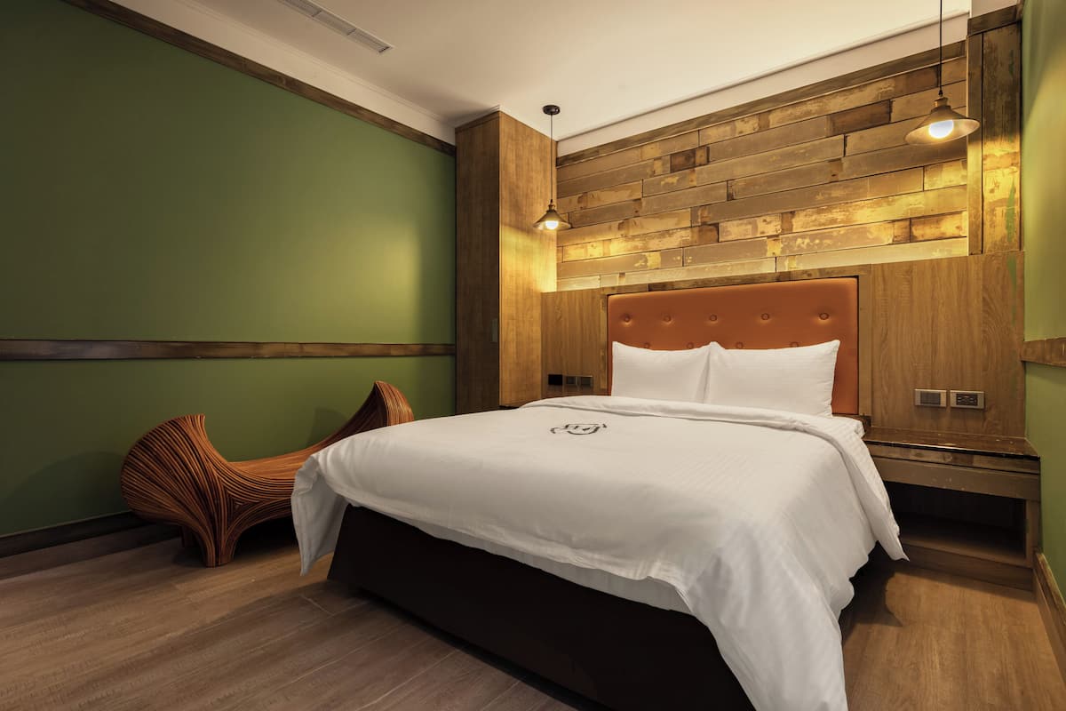 A modern bedroom with a wooden headboard, a large bed with white bedding, a unique curved bench, and a wooden wall panel.