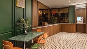 A check-in area with a reception desk, a clock, and a seating area with chairs and a table. - LUXIAINN (Tainan)