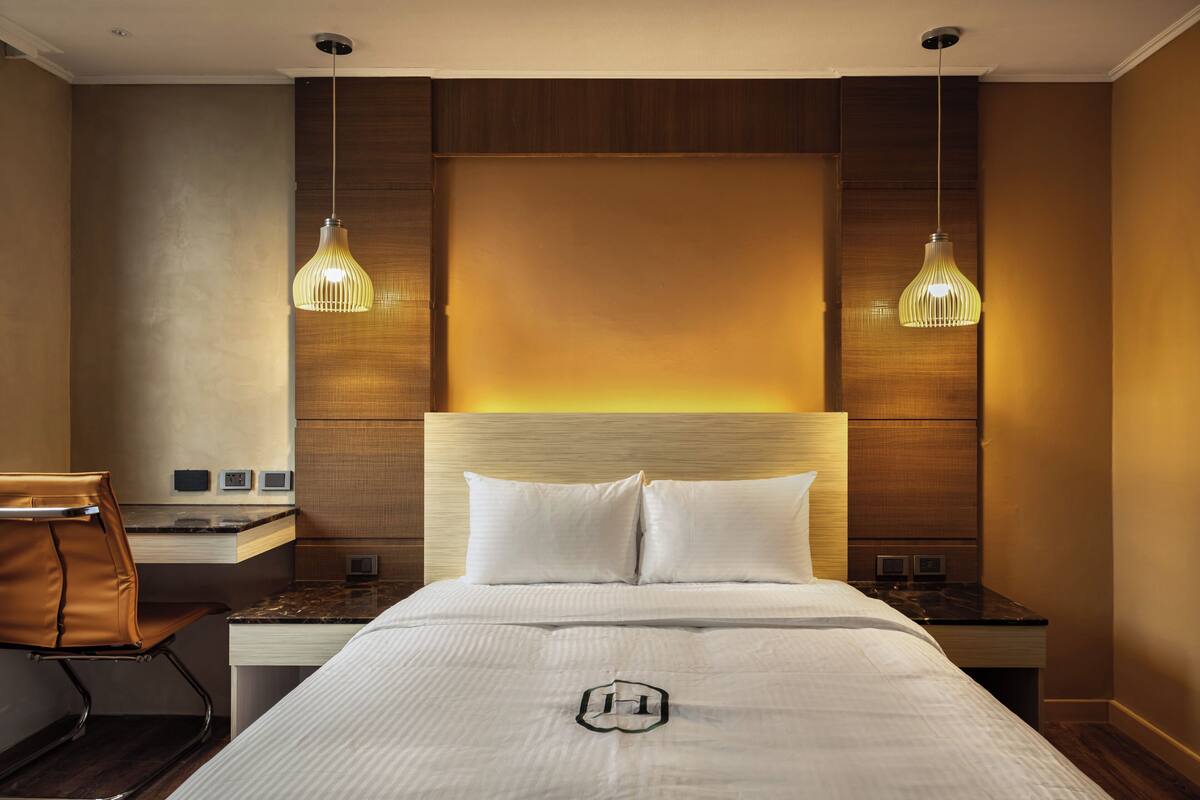 A hotel room with a large bed, two bedside tables, a desk, and a chair.