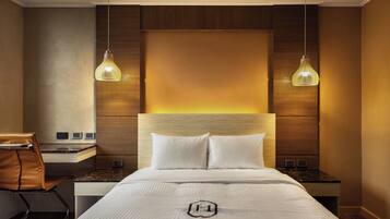 Ein Hotelzimmer mit einem großen Bett, zwei Nachttischen, einem Schreibtisch und einem Sessel.