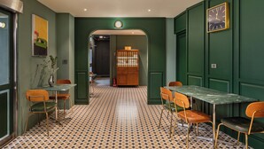 A room with a green wall, a clock, a table with chairs, and a patterned floor. - LUXIAINN (Tainan)