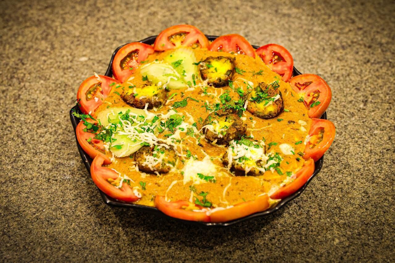 Un plato con albóndigas, tomates y queso, adornado con hierbas.