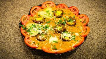 Un plato con albóndigas, tomates y queso, adornado con hierbas.