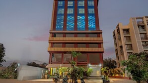 A tall hotel with a modern design, featuring large windows and a prominent sign at the top. - Treebo Arizona (Gandhinagar)