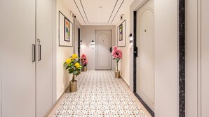 A hallway with a patterned floor, framed artwork on the walls, and potted plants. - Treebo Arizona (Gandhinagar)